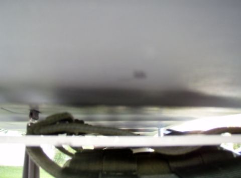 2005 Toyota 4Runner - The underside of a vehicle is visible, showing a metal panel with a strap or cable attached to it. Below this, a white horizontal bar runs…