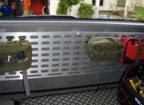2005 Toyota 4Runner - A metal panel with various pouches attached is mounted inside a vehicle. A green pouch with patches and a red first-aid kit are visible.