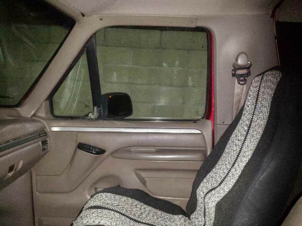 Interior of a Ford Bronco showing driver's side door panel, seat, and window.