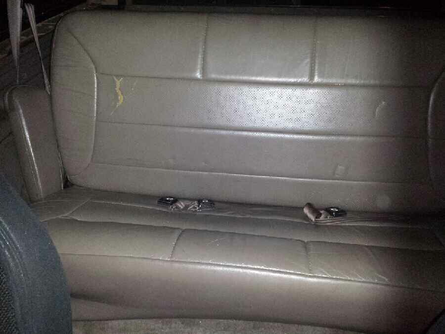 Gray leather rear bench seat in a vehicle with seatbelt buckles.
