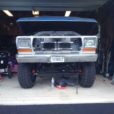 1978 Ford Bronco - A lifted 1978 Ford Bronco sits in a garage with its hood open, revealing the front end and suspension components. The vehicle has large off…