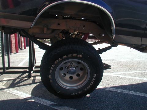 1988 Ford Bronco - Close-up of the rear wheel and suspension of a lifted truck, showing the Trailblazer A/T tire.