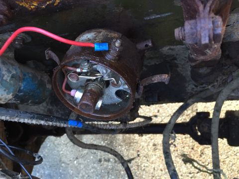 1946 Jeep Willys - This close-up image shows a rusty distributor cap with a red wire connected to it. The internal components of the distributor, including th…