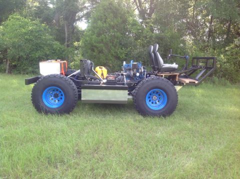 1992 Ford Bronco - A custom-built, open-frame vehicle with large tires and blue rims sits on a grassy lawn. The vehicle features two seats, an engine, a fuel…