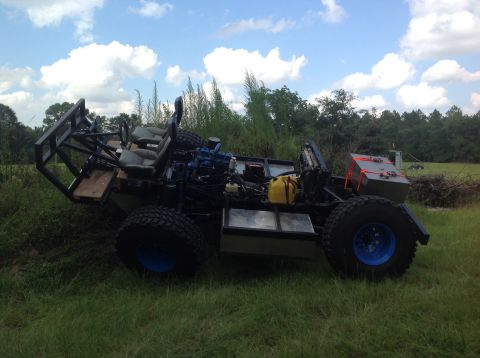 1992 Ford Bronco - A custom-built, open-air vehicle with large off-road tires and a blue wheel accent sits in a grassy field under a cloudy sky. The vehicle f…