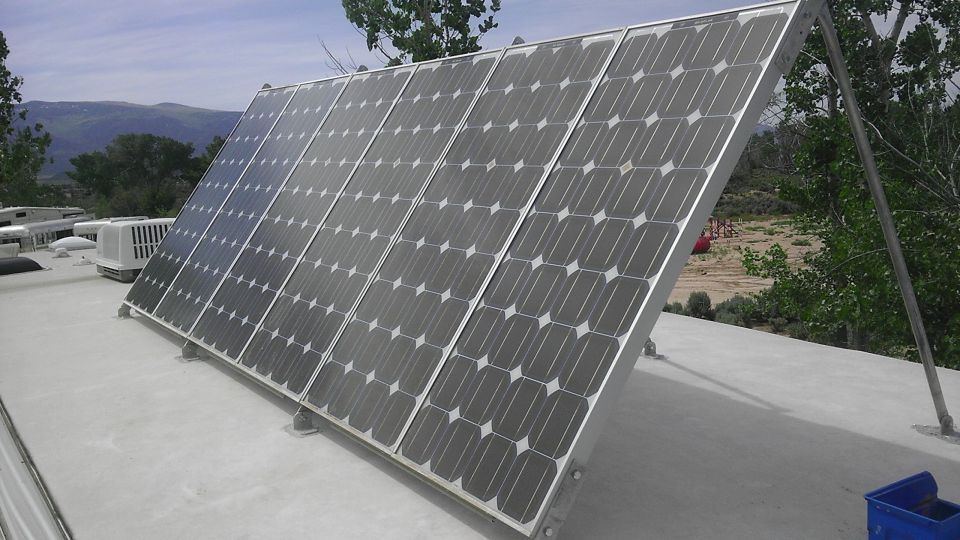 Solar panels mounted on a roof with trees and mountains in the background.