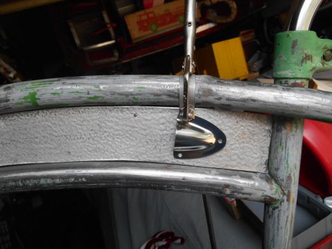 Chrome latch on silver panel attached to metal frame with chipped green paint.