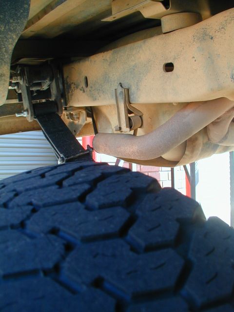 1988 Ford Bronco - Close-up view of the undercarriage, focusing on the leaf springs and exhaust system of an unidentified vehicle.