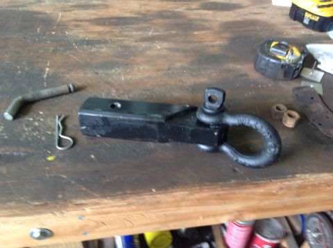 1992 Ford Bronco - A black hitch receiver with a shackle attached is shown on a wooden workbench. A bent metal pin and a cotter pin are also visible.