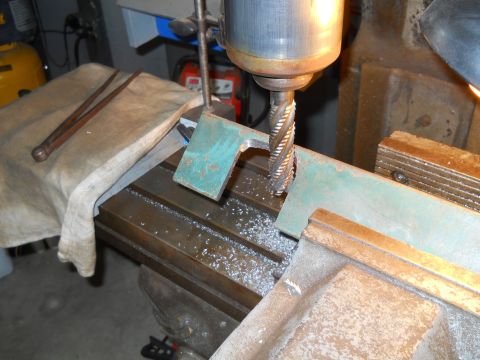 1992 Ford Bronco - A metal bracket is being machined on a milling machine. Metal shavings are visible on the machine bed.