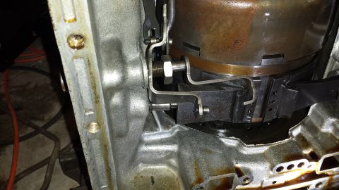 1978 Ford Bronco - Close-up view of the internal components of a transmission, possibly a torque converter, with metal brackets and fasteners visible. Oily re…