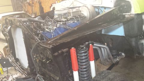 1978 Ford Bronco - The front end of a classic Ford Bronco undergoing restoration is shown, with the engine exposed and custom exhaust headers visible. The veh…