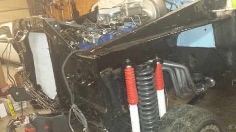 1978 Ford Bronco - The engine bay and front end of a classic Ford Bronco undergoing restoration. The vehicle is black with a partially installed radiator and…
