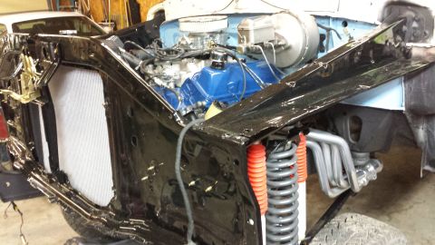 1978 Ford Bronco - The front end of a classic Ford Bronco is shown with the hood open, revealing a blue engine with chrome accents and exhaust headers. The ve…
