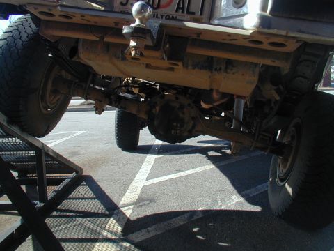 1988 Ford Bronco - The underside of a truck is shown, with its rear axle and suspension visible as it sits on a metal ramp.
