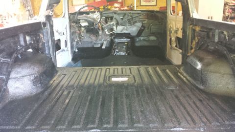 1978 Ford Bronco - The interior of a classic Ford Bronco is shown, with the bed and front cabin areas coated in a textured black protective material. The dash…