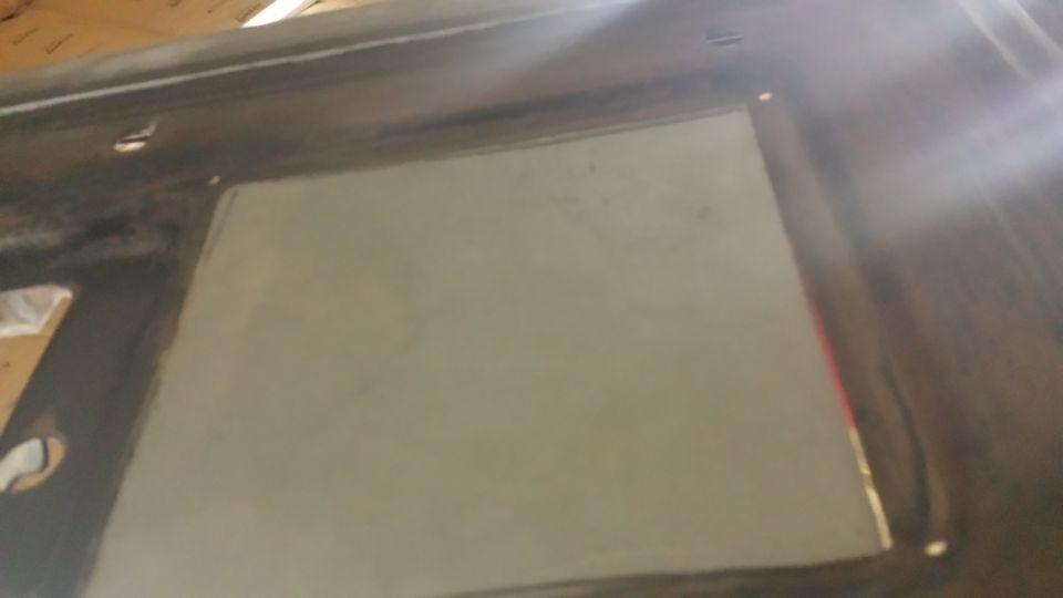 Vehicle interior with gray primer applied to a dark surface, possibly a repair.