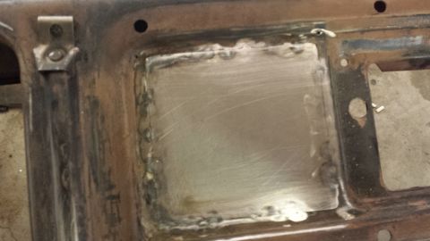 Welded patch on a rusty metal vehicle panel