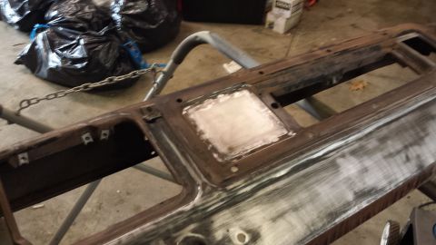 Rusty metal dashboard part with sanding and filler, supported by a stand.
