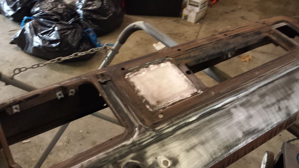Rusty metal dashboard part with sanding and filler, supported by a stand.
