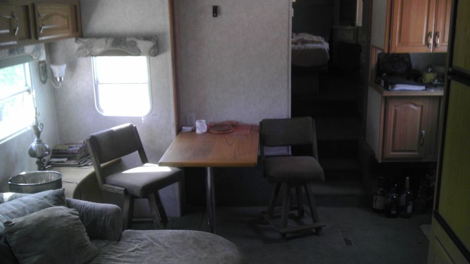 Interior of an RV with dining table, chairs, couch, and kitchenette.