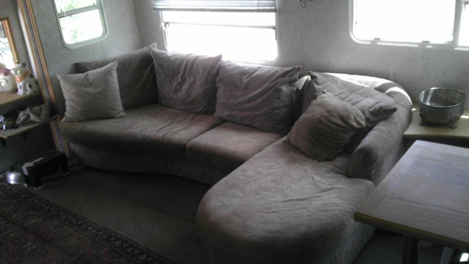 Interior scene of a room with a sectional couch and windows.