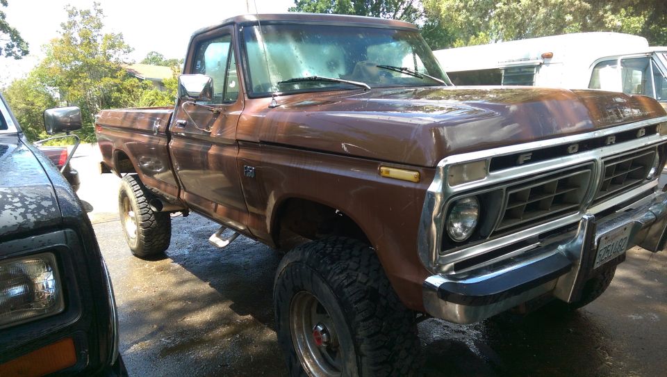 Brown 1970s Ford F-250 pickup truck with off-road tires and chrome bumper.