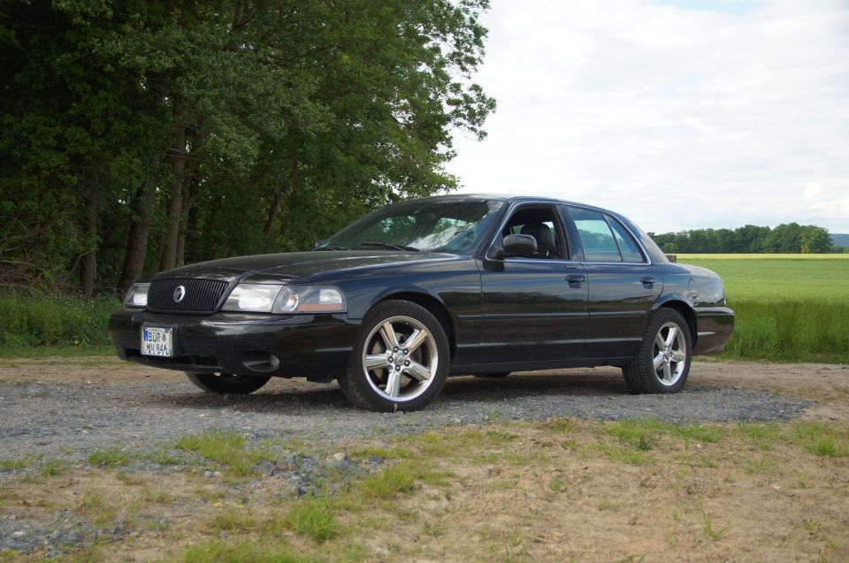 Black four-door sedan parked on a gravel road.