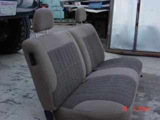 1992 Ford Bronco - A close-up view of a vehicle's bench seat, with a portion of the vehicle's exterior visible to the left.