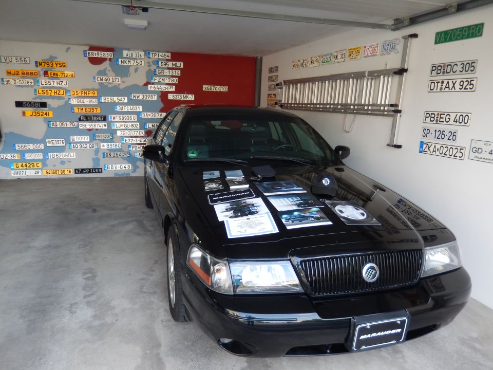 Black 2003 Mercury Marauder parked in a garage with license plates on the wall.