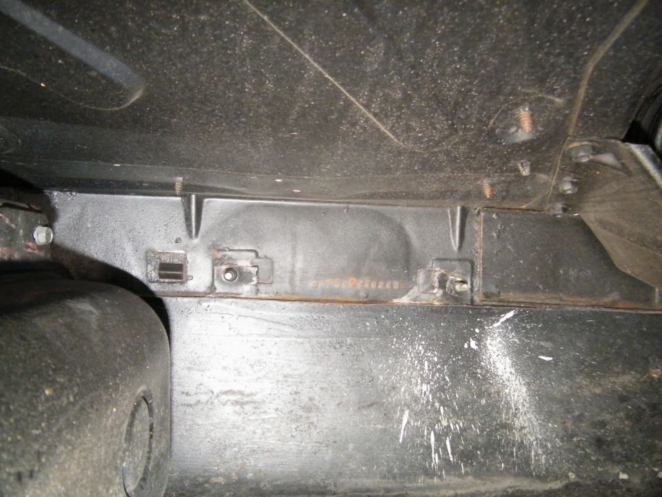 Underside of a vehicle showing frame, suspension, and tire.