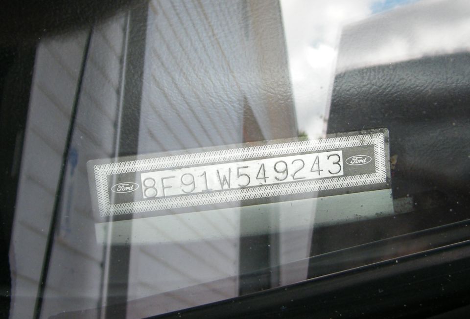 Ford windshield VIN tag reading 8F91W549243 viewed through the glass