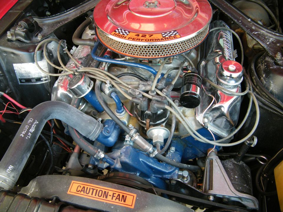 Vintage V8 engine with red air cleaner and chrome valve covers.