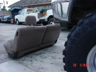 1992 Ford Bronco - A car seat is shown in front of a white pickup truck and a trailer. The image has a watermark at the bottom.