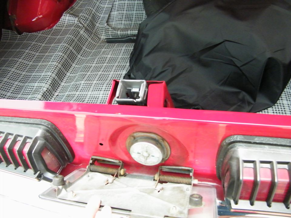 Interior of a red 1968 Mercury Cougar trunk lid showing latch mechanism and plaid lining.