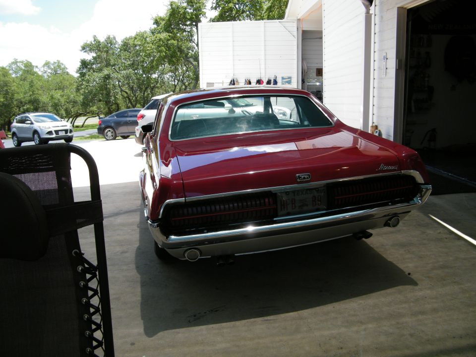 1968 Mercury Cougar rear view, dark red, parked in front of garage.