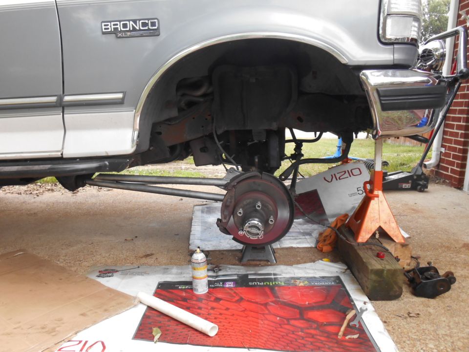 1994 Ford Bronco front passenger side, lifted with wheel removed, supported by jack stands.