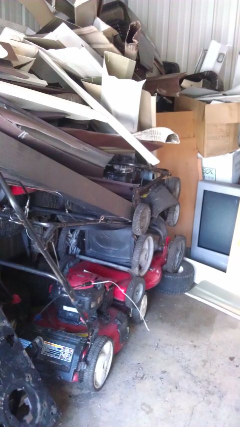 1994 Ford Bronco - Two red lawnmowers are stacked on top of each other in a cluttered garage. The top lawnmower is black and red, and the bottom lawnmower is…