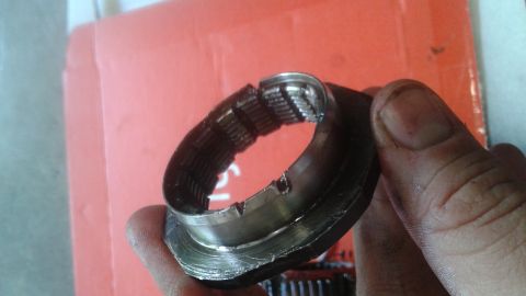 1996 Ford Bronco - A damaged metal bearing race with visible teeth and broken sections is held in a person's hand. The bearing appears to be covered in grease.