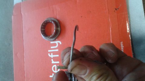 1996 Ford Bronco - A close-up shot shows a person's hand holding a metal spring and a small metal ring with teeth. The items are placed on an orange cardboard…