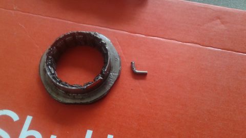 1996 Ford Bronco - A damaged metal ring with grease and a small L-shaped metal pin are shown against an orange surface.