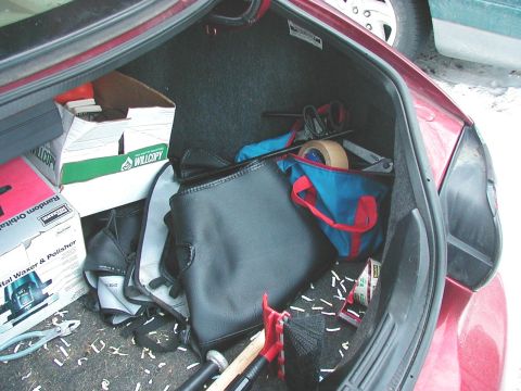 1997 Ford Taurus - The trunk of a red car is filled with various items, including tools, tape, and cardboard boxes.