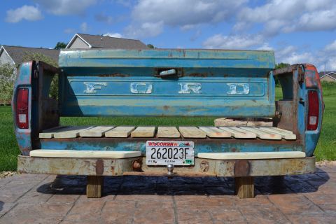 1994 Ford Bronco - A Ford truck tailgate has been transformed into a unique bench with a wooden seat and a license plate.