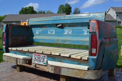 1994 Ford Bronco - A repurposed Ford truck bed, now a bench, sits outdoors with a Wisconsin license plate visible.