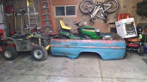 1994 Ford Bronco - An ATV and a lawnmower sit next to a weathered blue truck bed inside a cluttered garage.