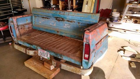 1994 Ford Bronco - A repurposed Ford truck bed serves as a rustic bench, showing signs of age and weathering.