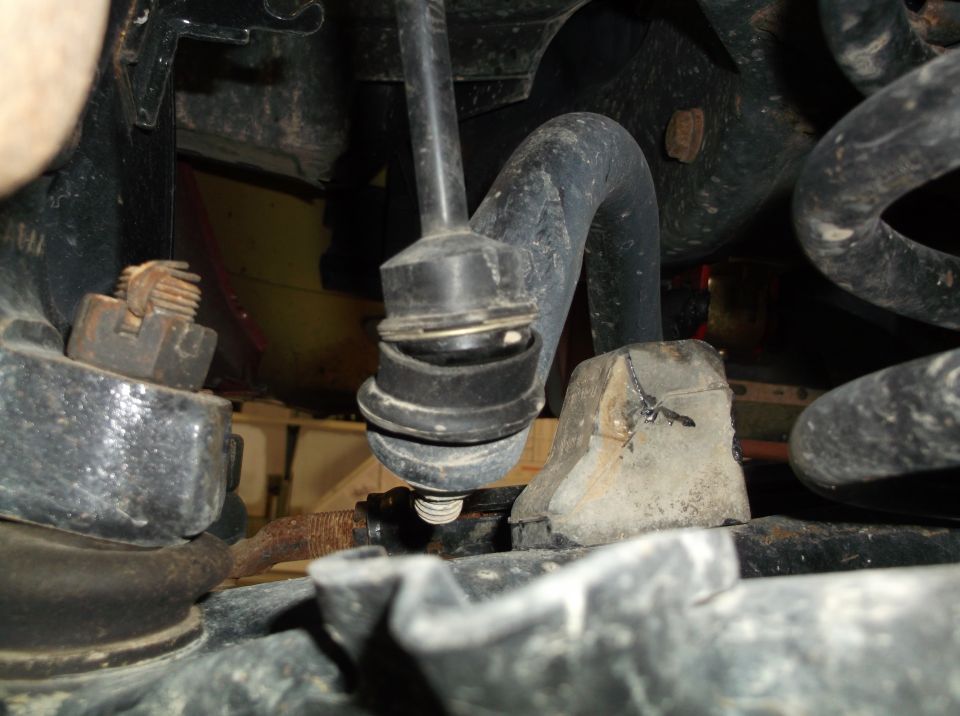 Close-up of a vehicle's sway bar end link and surrounding suspension parts, showing rubber bushings and metal components