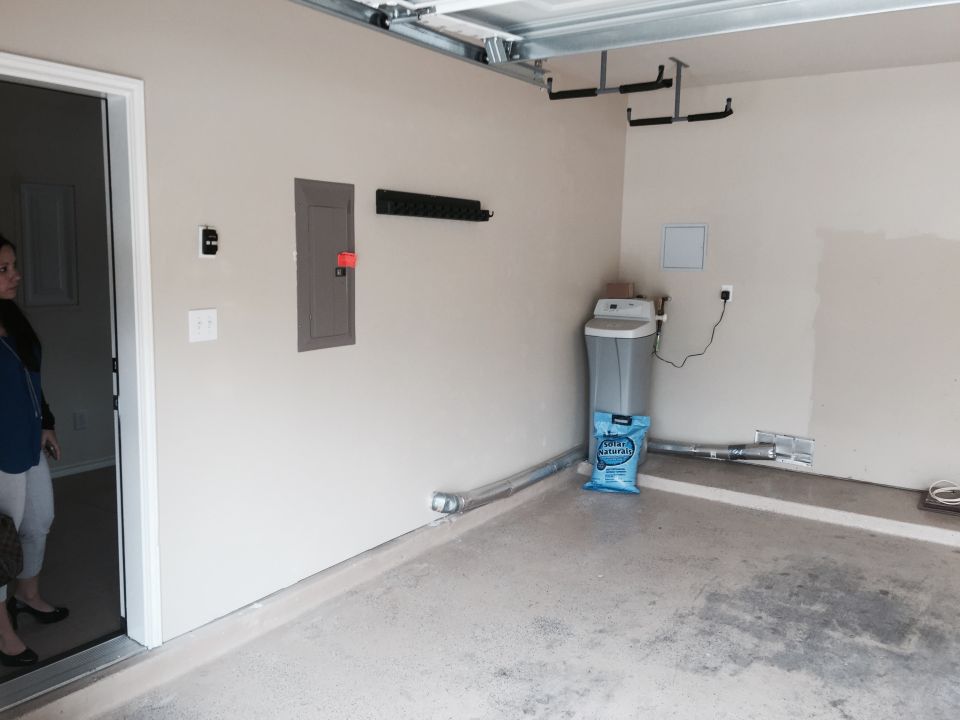 Garage interior with water softener, electrical panel, and overhead storage racks