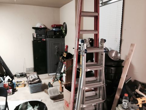2015 Ford Deluxe - A cluttered garage scene with storage units, ladders, and miscellaneous items.