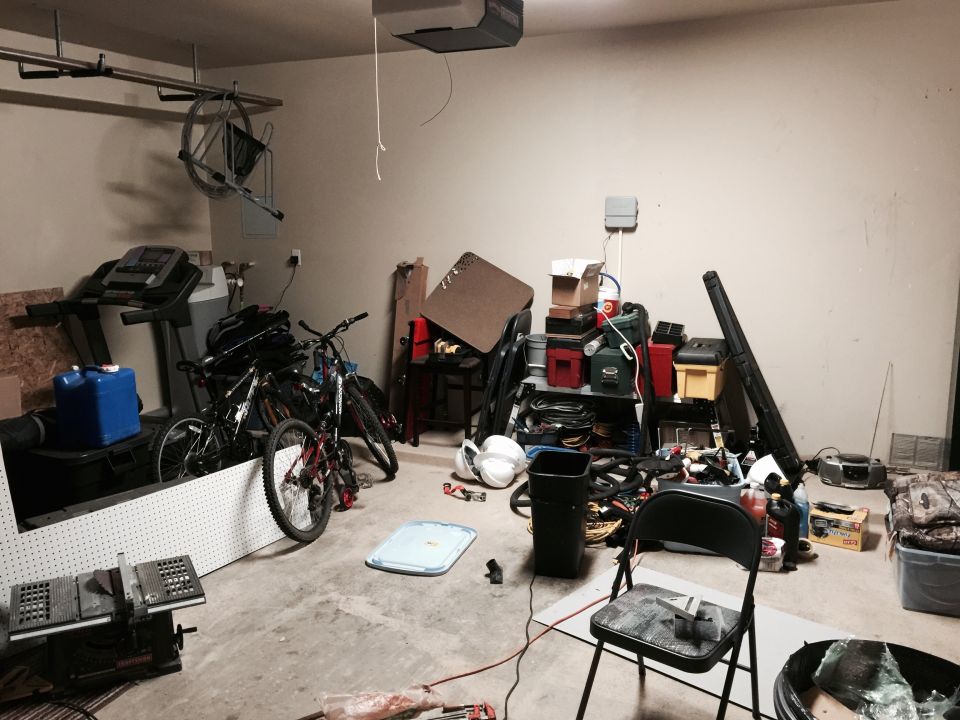 Cluttered garage with treadmills, bicycles, tools, and storage shelves